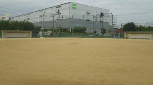 後方に大きな物流施設が見える広々としたグラウンドの深江浜公園野球場の写真