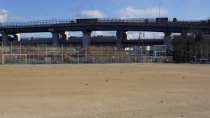 後方に高架線の高速道路が見える広々としたグラウンドの小野浜公園球技場の写真