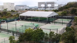テニスコートがフェンスで仕切られ、5面のテニスコートと奥に白い大きなテントが設置されている西神南テニスガーデンの写真